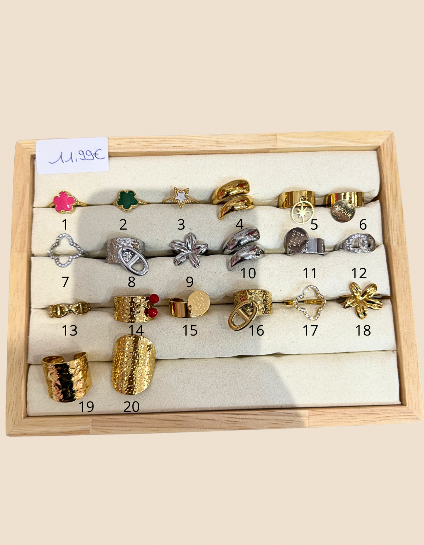 Stainless steel rings, multiple designs in gold and silver on a wooden display tray